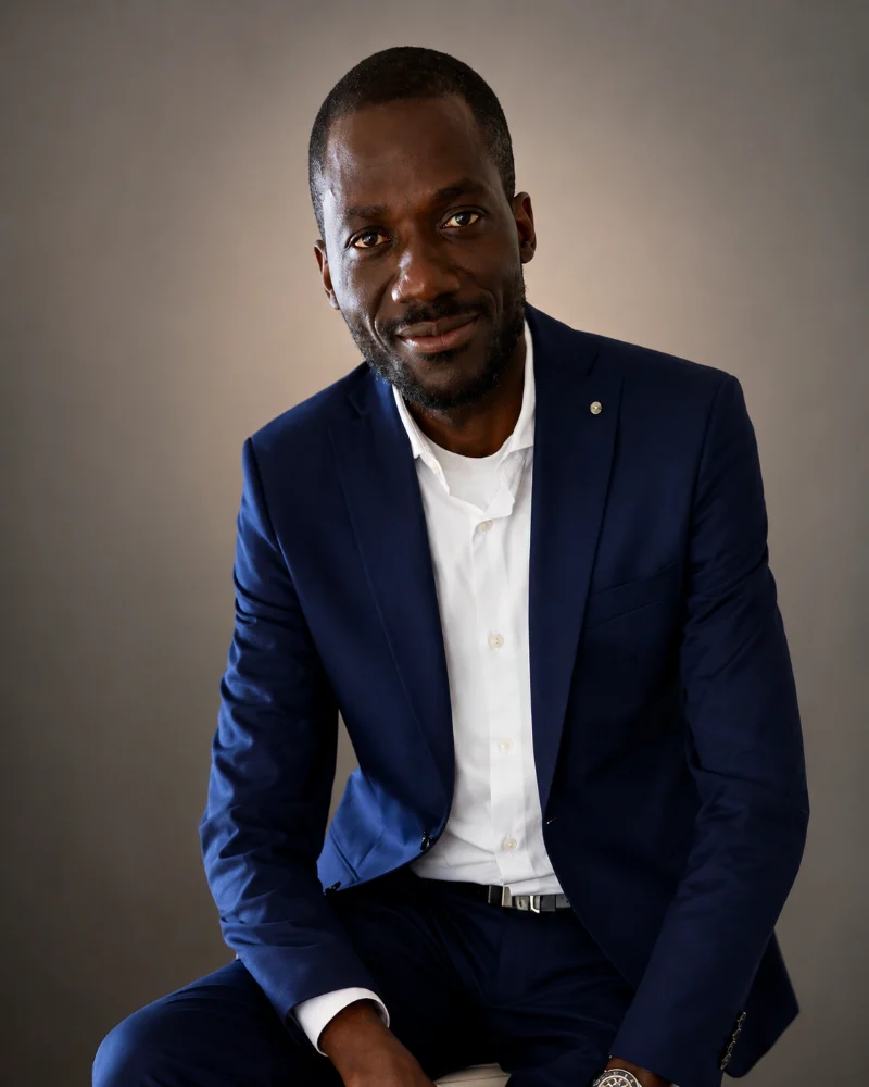 Christian M. Kaba, seated portrait in a navy suit.